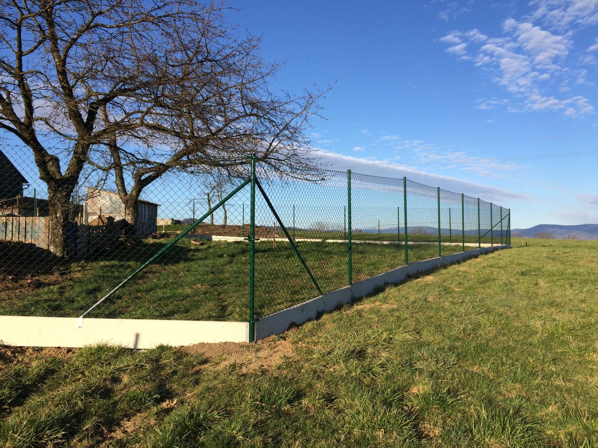 Pletivový plot s podhrabovou deskou v krajině — realizace Stavíme ploty