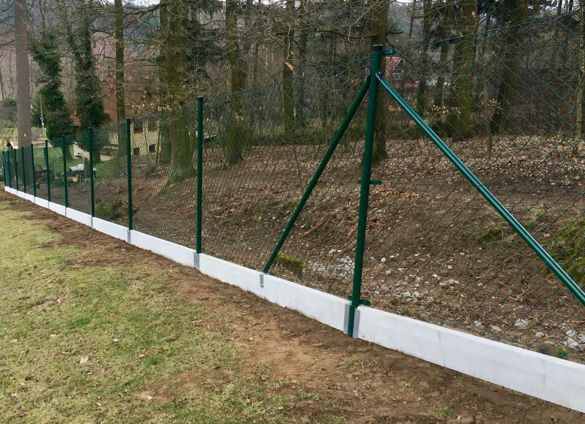 Pletivový plot s podhrabovou deskou na svahu — realizace Stavíme ploty