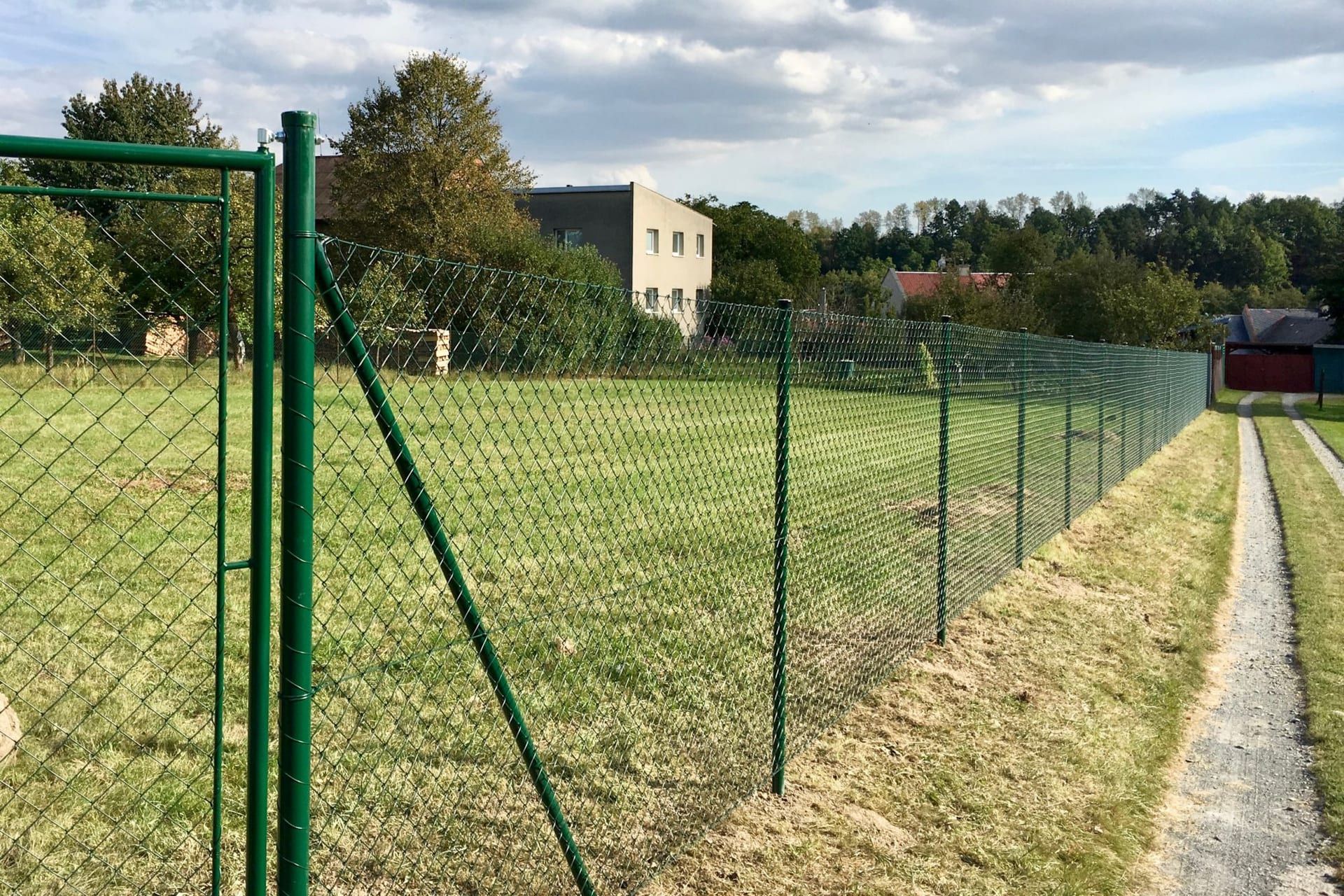 Zelený pletivový plot s brankou na venkově — realizace Stavíme ploty